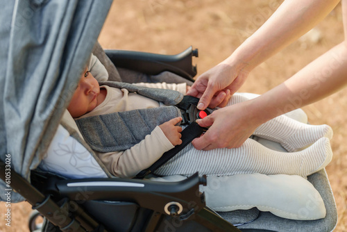 woman fastening belt on stroller with crying baby