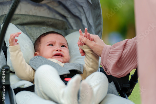 mother consoling her infant baby crying in stroller