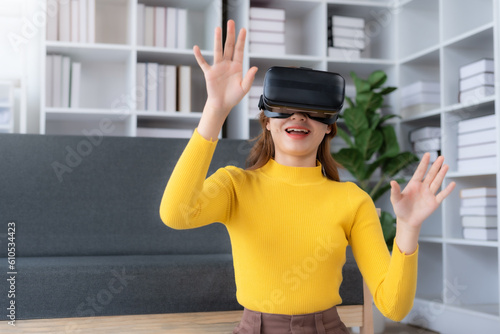 Smiling woman having fun using VR glasses playing game at home happily and enjoy virtual reality.