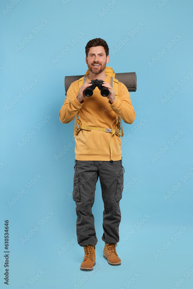 Man with backpack and binoculars on light blue background. Active tourism Man with backpack and binoculars on light blue background. Active tourism