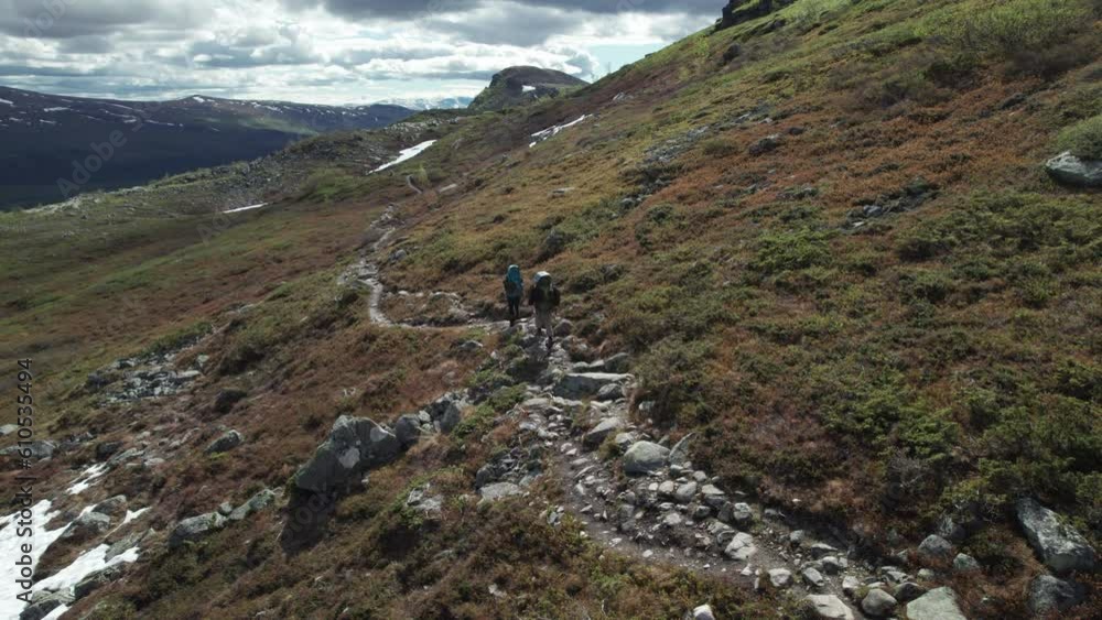 Aerial Top Shot of Young Hiker Couple walking on the Kungsleden Trail in Northern Sweden, Lapland, Hikers with heavy Backpacks, Serene Mountain Landscape Aerial Top Shot of Young Hiker Couple walking on the Kungsleden Trail in Northern Sweden, Lapland, Hikers with heavy Backpacks, Serene Mountain Landscape
