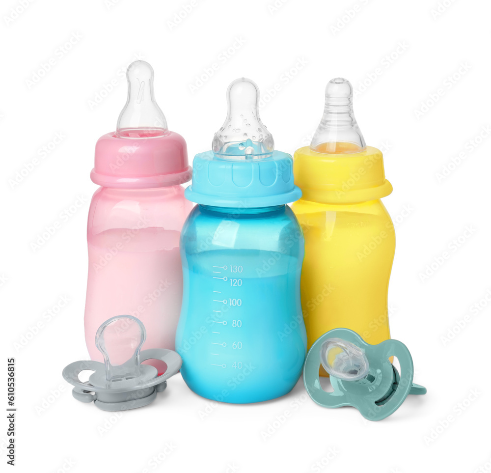 Feeding bottles with milk and pacifiers on white background Feeding bottles with milk and pacifiers on white background