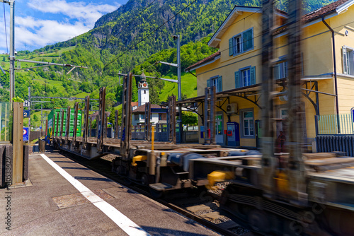 Freight train passing Swiss railway station Sisikon on a sunny spring noon. Photo taken May 22nd, 2023, Sisikon, Switzerland.