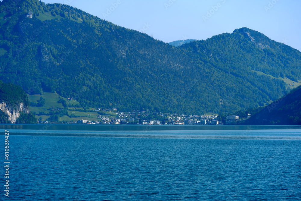 Scenic view of Lake Lucerne with Swiss Alps and mountain panorama and City of Brunnen in the background on a sunny spring day. Photo taken May 22nd, 2023, Lake Uri, Switzerland.
