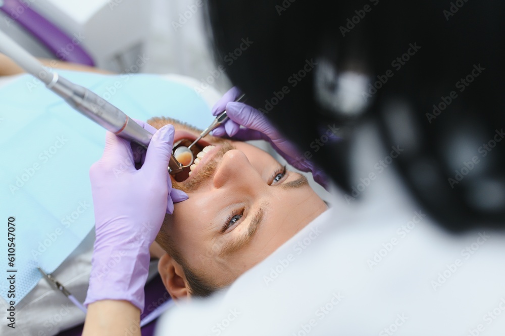 Fototapeta premium Periodontal Services. Closeup Shot Of Smiling Man Getting Treatment In Stomatologic Clinic, Dentist Doctor In Gloves Using Sterile Dental Tools For Examining Teeth Of Male Patient