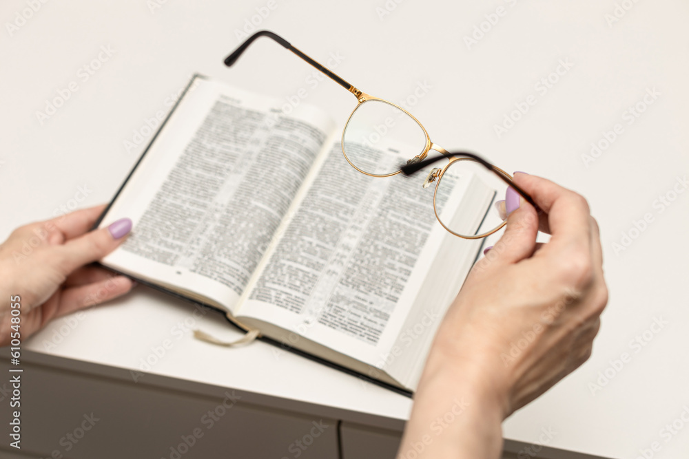 woman putting on glasses before reading a book. woman putting on glasses before reading a book.