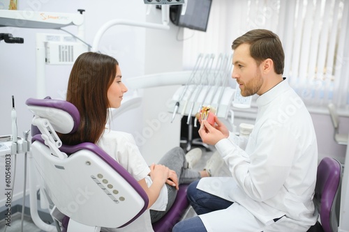 Doctor shows on a plastic tooth sample or model different methods of teeth treatment