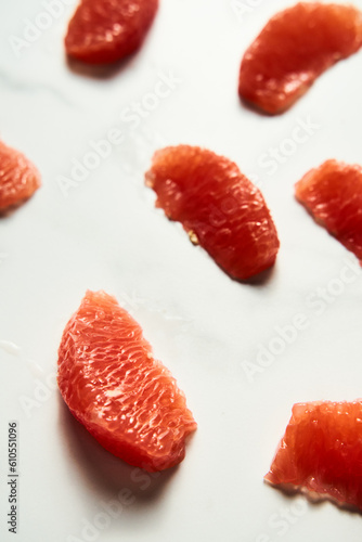 Peeled and sliced, divided in sections grapefruit on the white marble countertop. Bright, hey-key vertical photo.Top view food photo