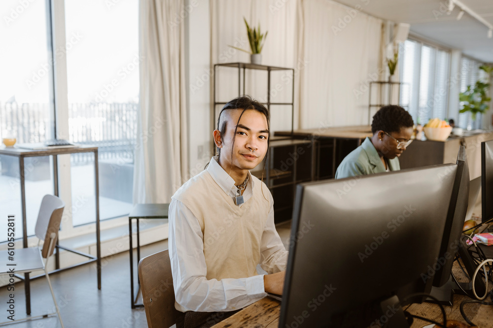 Portrait of hipster young male programmer sitting at computer desk in office Portrait of hipster young male programmer sitting at computer desk in office