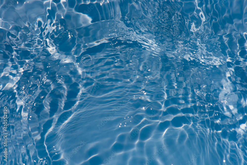 Blue water with ripples on the surface. Defocus blurred transparent blue colored clear calm water surface texture with splashes and bubbles. Water waves with shining pattern texture background.