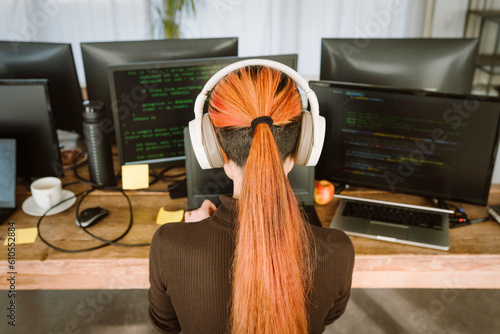 Rear view of female programmer working on laptop in creative office photo