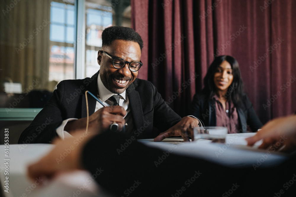 Happy mature businessman examining documents sitting in board room at office Happy mature businessman examining documents sitting in board room at office