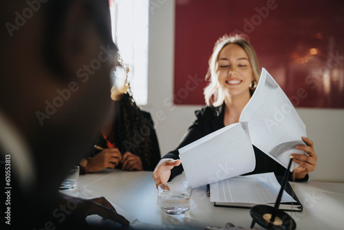 Smiling businesswoman reading agreement sitting in board room at office photo