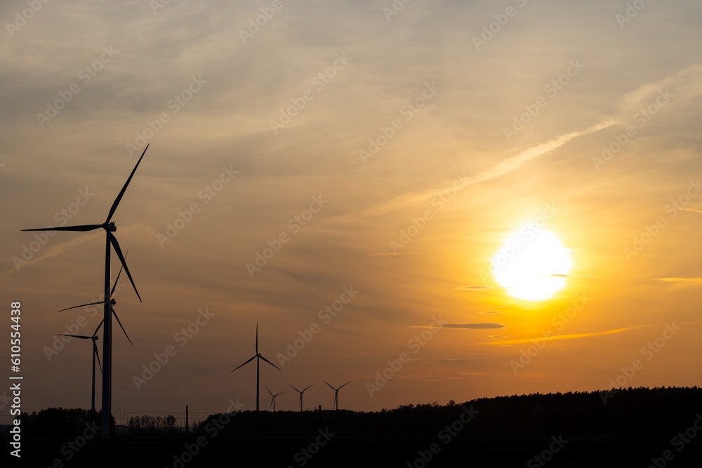 Wind turbines against the background of an orange setting sun. Renewable energy sources in the fight against high energy costs Wind turbines against the background of an orange setting sun. Renewable energy sources in the fight against high energy costs