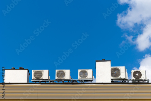 Many air conditioners on the roof of the building. Shot on a sunny day against a blue sky. photo