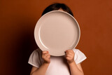 Cover Face with Empty Plate Child on Brown Background