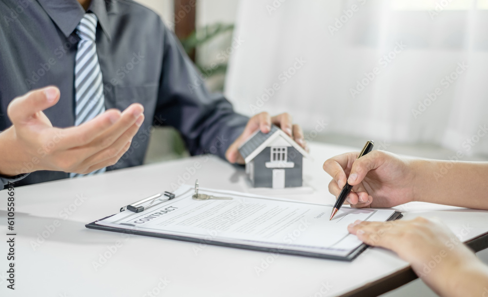 A real estate agent with a home model is talking to clients about renting a house and buying home insurance and contracting the contract after the formal negotiation is completed A real estate agent with a home model is talking to clients about renting a house and buying home insurance and contracting the contract after the formal negotiation is completed