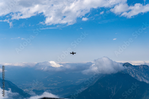 Drone flying in the blue sky with clouds over the stunning Alps mountains peaks in Austria. Innovation photography concept.