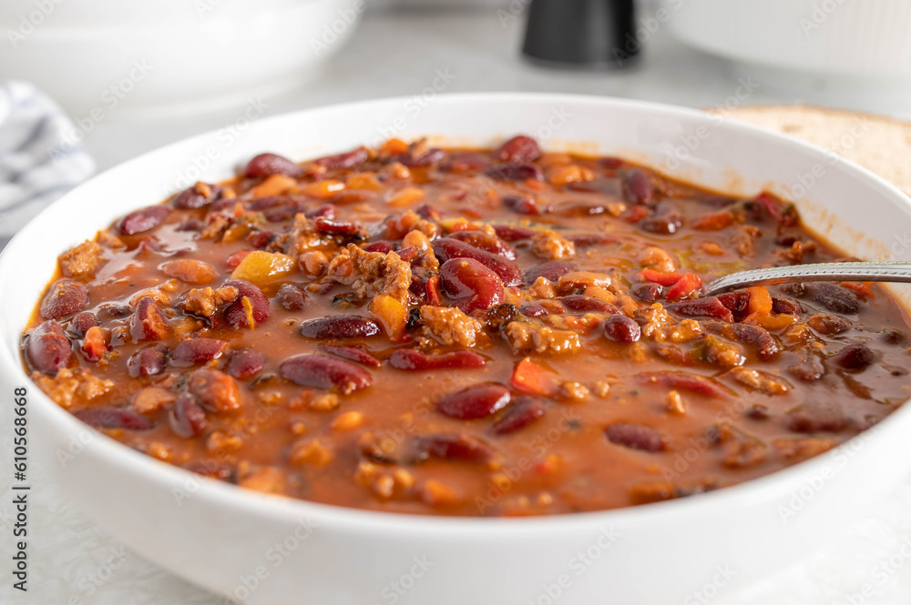 Kidney bean stew with ground beef, tomatoes, bell peppers, onions, garlic and herbs on a plate with spoon