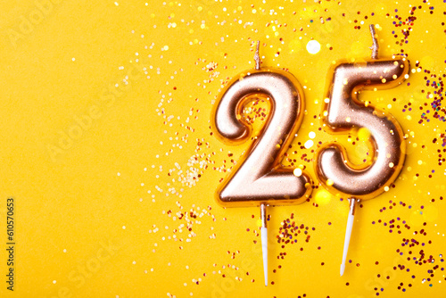 Gold candles in the form of number twenty five on yellow background with confetti. 25 years anniversary celebration.