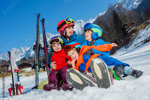 Mother with small kids sit in the snow wear sport outfit