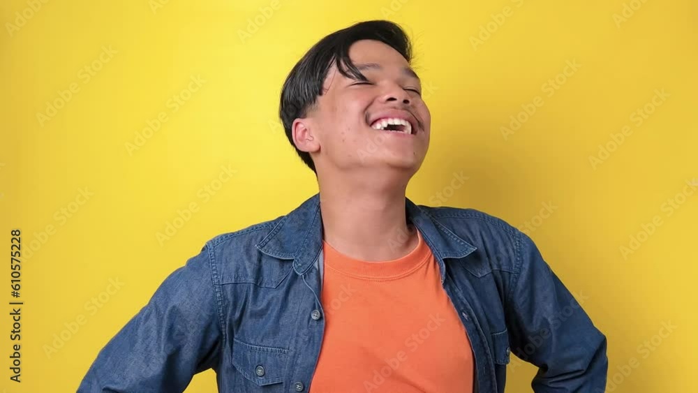 Young asian man in casual style laugh out loud isolated on yellow background Young asian man in casual style laugh out loud isolated on yellow background