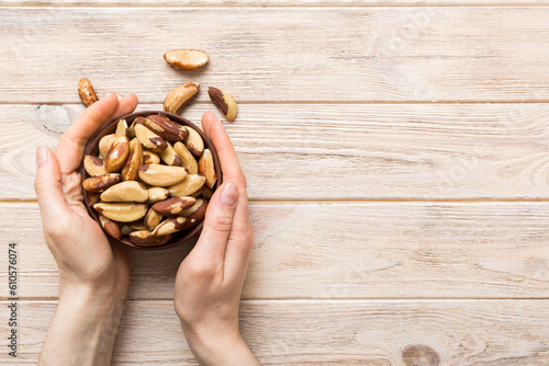 Woman hands holding a wooden bowl with brazil or bertholletia nuts. Healthy food and snack. Vegetarian snacks of different nuts photo