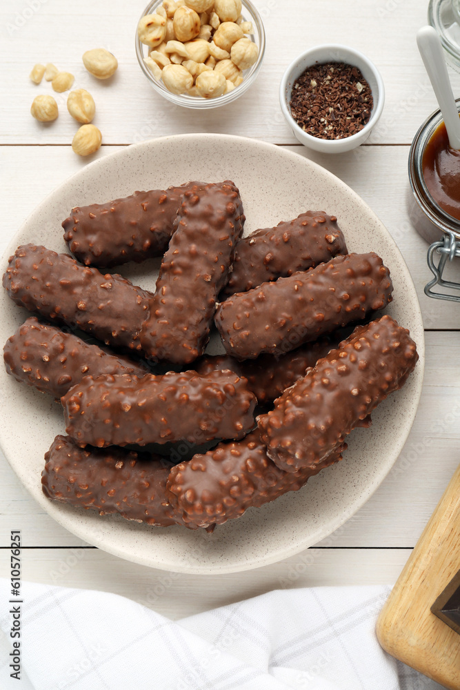 Tasty chocolate bars with caramel and nuts on white table, flat lay Tasty chocolate bars with caramel and nuts on white table, flat lay