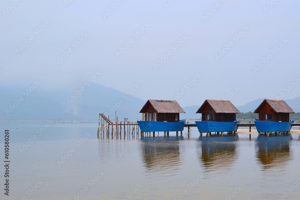 Wooden fishermens huts built on a calm lake with pier and mountains in the background