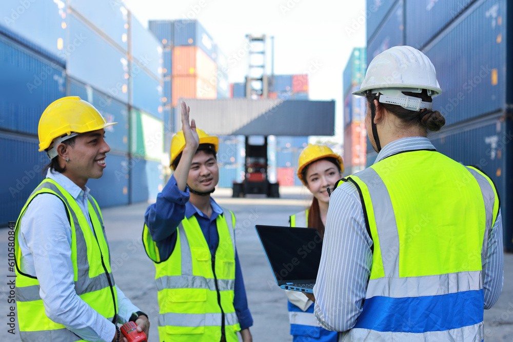 Group of multiethnic technician engineer in protective uniform standing and using computer, walkie talkie radio and tablet while.working together and controlling at container cargo site industrial Group of multiethnic technician engineer in protective uniform standing and using computer, walkie talkie radio and tablet while.working together and controlling at container cargo site industrial