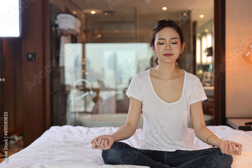 Fotografia Asian woman wearing white sleepwear practicing mediate yoga