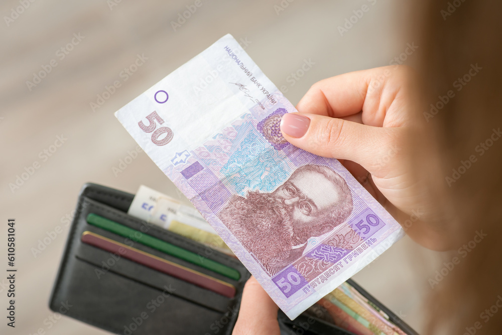 Female paying for something with 50 hryvnia. Hryvnia banknote and a purse in hands of a girl