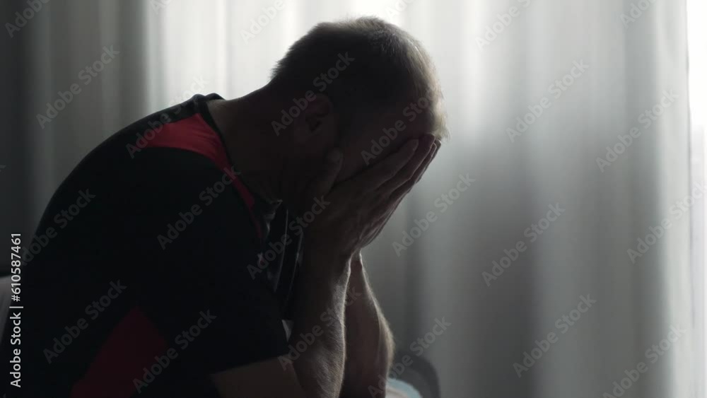 Unhappy mature middle age man sitting on a bad. Portrait of Deppressed thoughtful caucasian man. Concept of age crysis Unhappy mature middle age man sitting on a bad. Portrait of Deppressed thoughtful caucasian man. Concept of age crysis