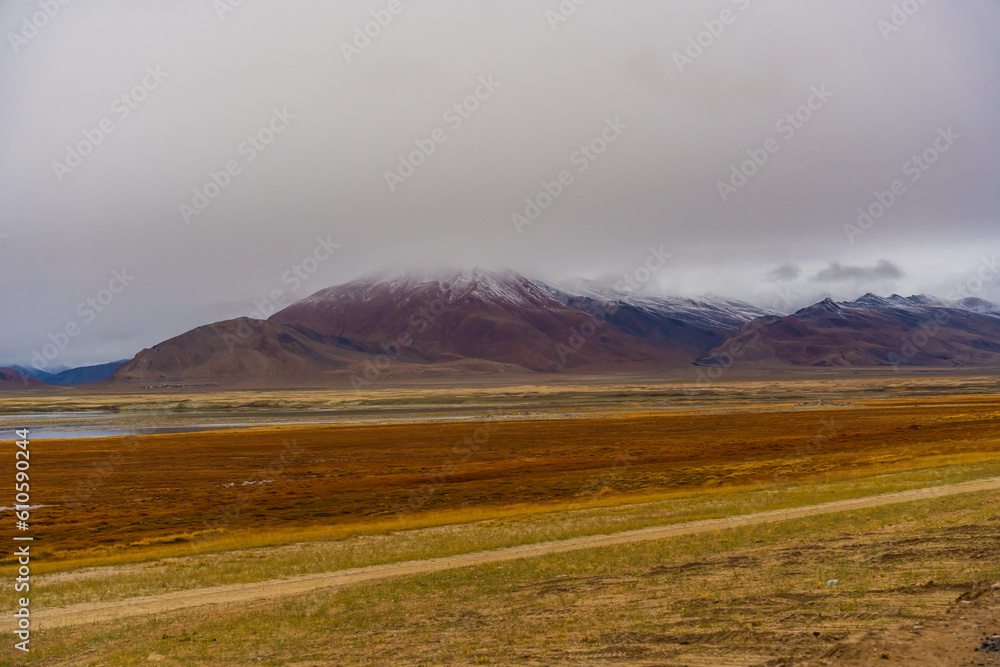 withered grass field, the mountain and cloud sky at Tso Kar lake, Beautiful scenery along the way at Ladakh, India. The Tso Kar or Tsho kar is a fluctuating salt lake withered grass field, the mountain and cloud sky at Tso Kar lake, Beautiful scenery along the way at Ladakh, India. The Tso Kar or Tsho kar is a fluctuating salt lake