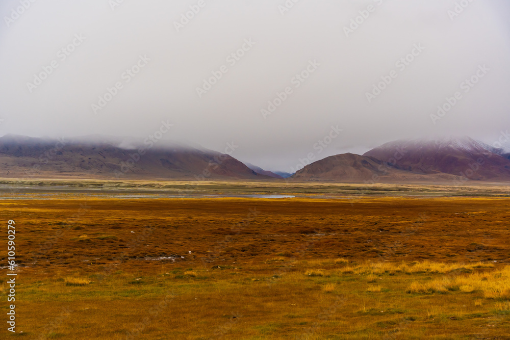 withered grass field, the mountain and cloud sky at Tso Kar lake, Beautiful scenery along the way at Ladakh, India. The Tso Kar or Tsho kar is a fluctuating salt lake withered grass field, the mountain and cloud sky at Tso Kar lake, Beautiful scenery along the way at Ladakh, India. The Tso Kar or Tsho kar is a fluctuating salt lake