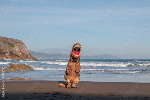 T-rex on the ocean beach in Zumaia, Spain. Dinosaur next to sea..
