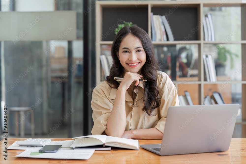 Obraz premium Business woman, portrait and smile at desk in office for paperwork, laptop. Happy, young or confident female worker with pride planning project at table in startup company