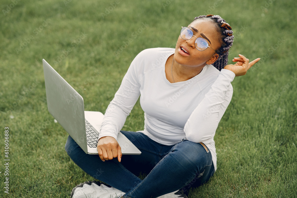 Fototapeta premium Black girl in a summer city with laptop