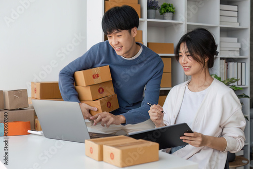 Happy couple people packing parcel boxes, couple lover checking order online on laptop at home