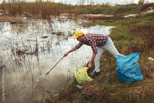 Volunteer and environmental activist cleaning dirty lake shore filled with trash.
