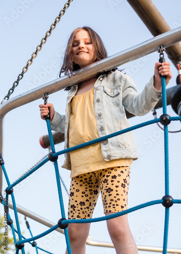 A happy girl at a playground. The girl is playing on net ropes.