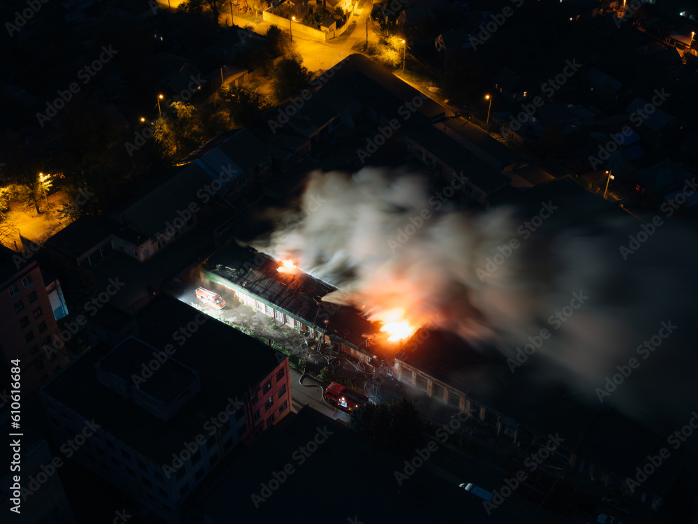 Aerial view of an industrial building that is on fire. Night fire. Smoke in the sky Strong fire in the warehouse.