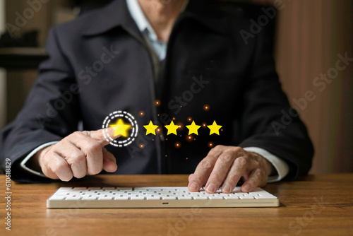 Man hand touch on virtual screen to give fiive star symbol on desktop keyboard to increase rating of products and services concept, Customer service and business satisfaction survey,selective focus.