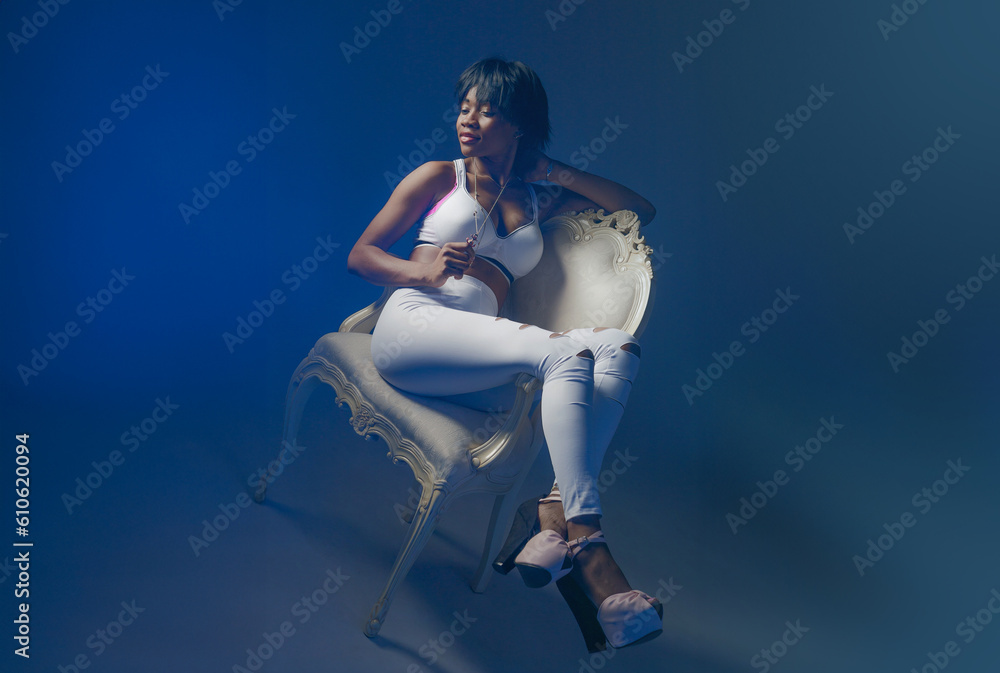 Attractive woman. Girl sits on chair with her legs stretched out. African American model. Fashion girl top view. Portrait ethnic girl. Belle in white stylish clothes. African American fashion model