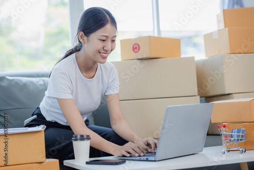 Starting a Small Business Entrepreneur Freelance Asian woman who is happy to work using a laptop with a box Cheerful successful online marketing packaging box and send SME concept