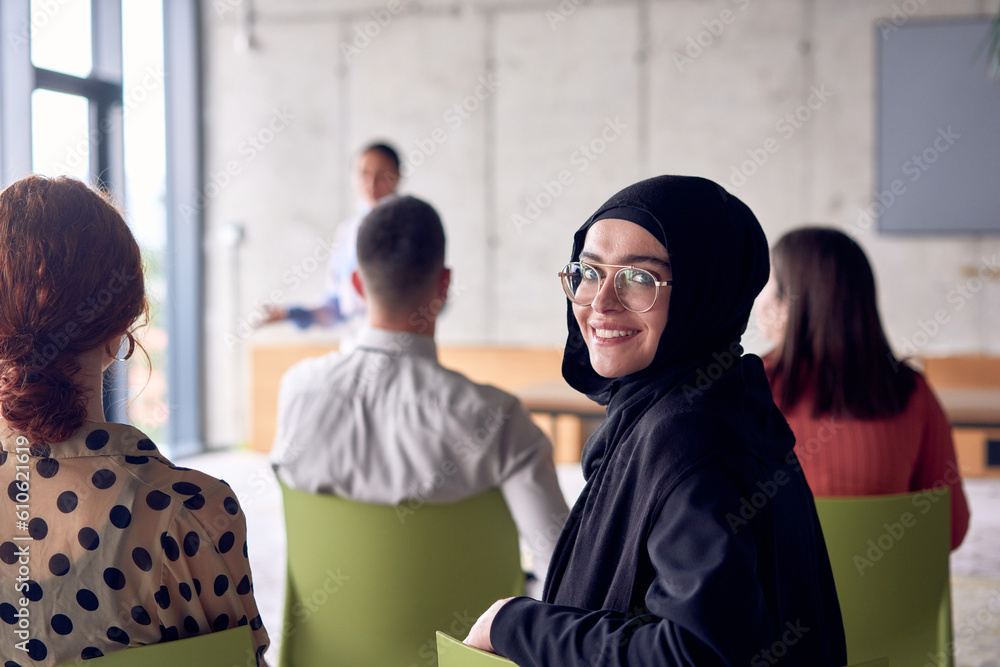 A young hijab woman entrepreneur is attentively listening to a presentation by her colleagues, reflecting the spirit of creativity, collaboration, problem-solving, entrepreneurship, and empowerment.
