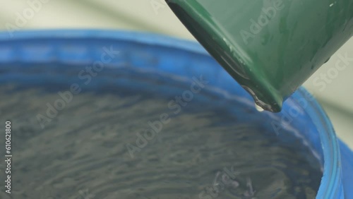 Water drips down the drain pipe after the rain into a blue plastic barrel