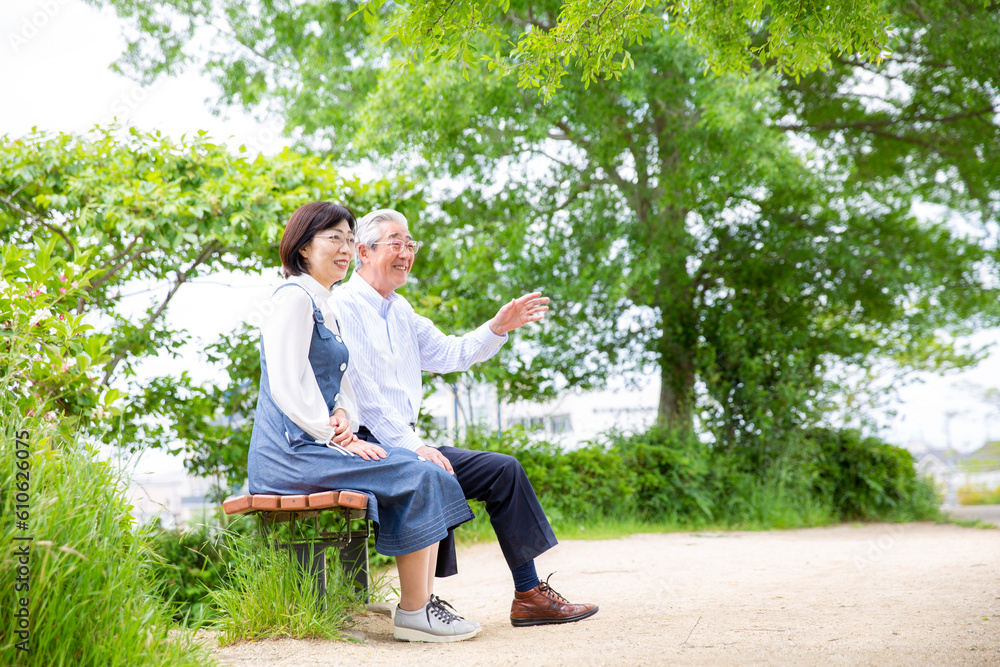 Fototapeta premium 公園のベンチ、笑顔で会話する日本人のミドル夫婦