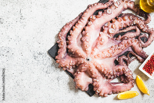 raw fresh octopus on gray stone with lemon and pink pepper