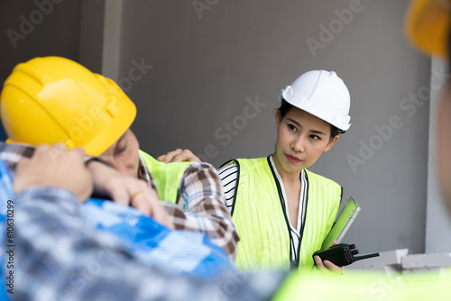 Foreman user radio to nurse for first aid Construction worker faint in construction site because Heat Stroke. Worker with safety helmet take a nap because so are tired from working in the hot sun photo